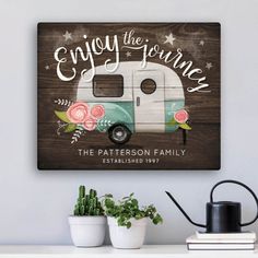 a wooden sign that says enjoy the journey with an old camper and flowers on it