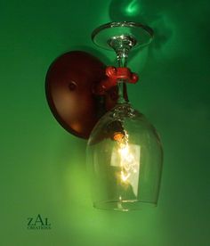 a wall light with a glass shade hanging from it's side on a green wall