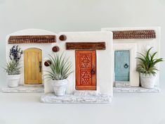 three pots with plants in them are next to a house shaped like a door and window