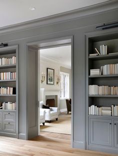 an open door leading to a living room filled with furniture and bookshelves full of books