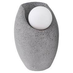 a gray vase with a white ball in it's center on a white background