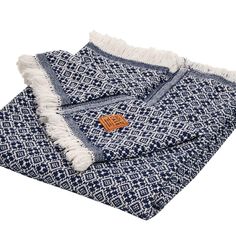 the blue and white blanket has fringes on it, with an orange tag that reads