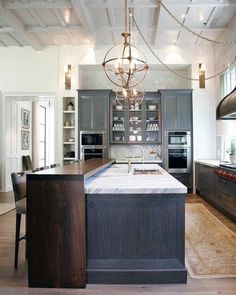 a large kitchen with an island and chandelier hanging from the ceiling above it