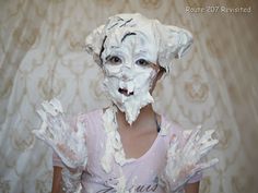 a woman with white paint on her face and hands in front of a wallpapered background