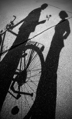 the shadow of a person standing next to a bike