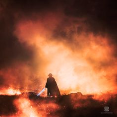 a man standing on top of a hill in front of a large fire filled sky