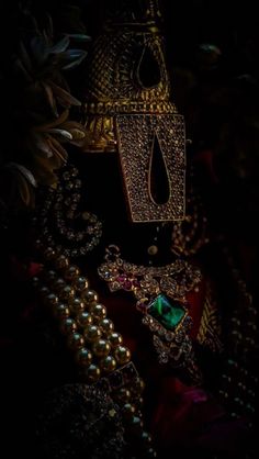 a close up of some jewelry on a dark surface with flowers in the foreground