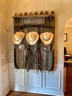 three cowboy hats hanging on a wall with the word welcome written above them and four other hat racks