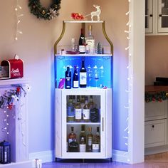 a lighted bar cart with bottles of wine in front of a christmas wreath on the wall