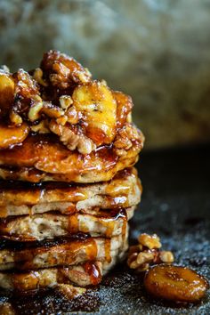 a stack of pancakes covered in syrup and nuts