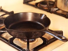 an old cast iron skillet sitting on top of a gas stove with two burners