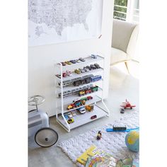 a white shelf filled with toys next to a wall mounted map in a living room