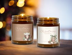 two candles sitting on top of a wooden table next to a christmas ornament