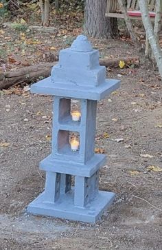 a blue candle holder sitting on top of a dirt ground