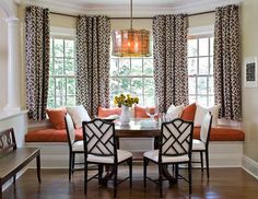 a dinning room table with four chairs and a bench in front of the window