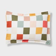 a pillow with multicolored squares on the front and back of it, sitting on top of a white surface