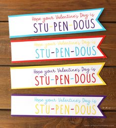 four colorful valentine's day signs on top of a wooden table