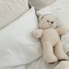 a teddy bear laying on top of a white pillow