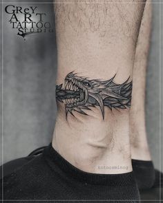 a man's foot with a dragon tattoo on the side of his leg and an inscription that reads grey art tattoo studio