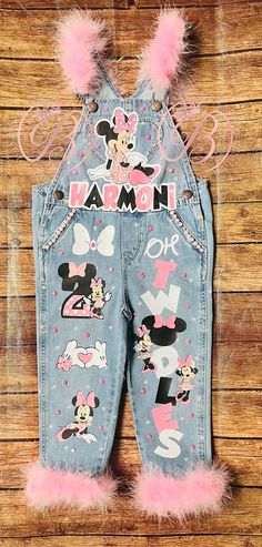 a pair of denim overalls with minnie mouse patches and pink pom - poms