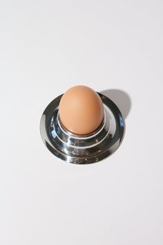 an egg sitting on top of a metal object in the middle of a white surface