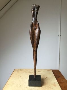 a bronze statue sitting on top of a wooden table