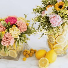 two vases filled with flowers and lemons next to each other on a table