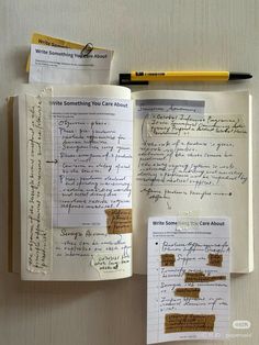 an open notebook with writing on it next to a pen and paper clippings