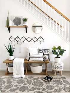 a living room filled with furniture and plants on top of a wooden table next to a stair case