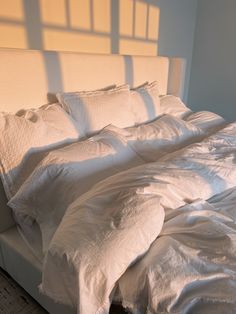 an unmade bed with white sheets and pillows