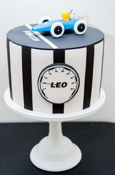 a black and white striped cake with a blue car on it's top tier