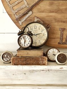 an old clock sitting on top of a wooden shelf next to other clocks and books