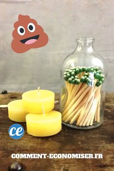 some candles are next to a glass jar with matches and an emoticive face