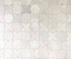 a white tile wall with an intricate pattern on it's side and the floor