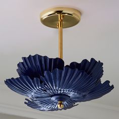 a blue flower shaped light fixture hanging from the ceiling in a room with white walls