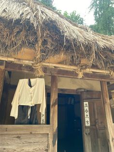 clothes hanging out to dry in front of an old building with thatched roof and door