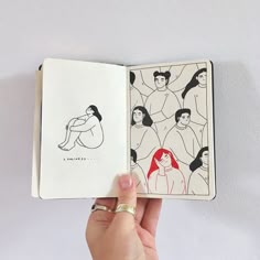 a hand holding an open book with drawings on it