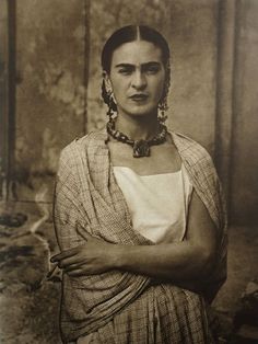 an old black and white photo of a woman with her arms crossed, looking at the camera