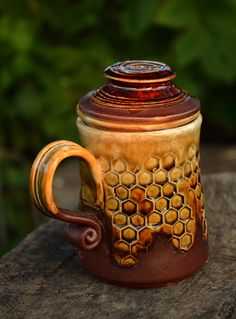 a brown and yellow ceramic mug sitting on top of a wooden table