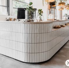 a white tiled counter with plants in vases at the top and on the side