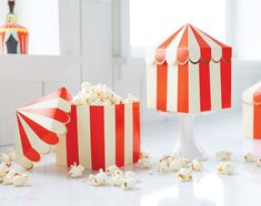 three red and white striped boxes with popcorn on the floor in front of some chairs