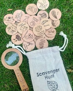 a bag filled with wooden badges next to a magnifying glass on the grass