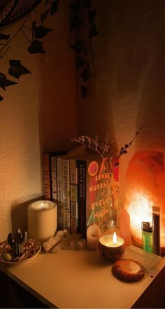 a table topped with candles and books next to a wall