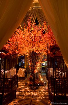 the entrance to an elegant wedding venue decorated with orange flowers and white draping