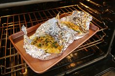 two foil wrapped burritos sitting on top of an oven rack in the oven