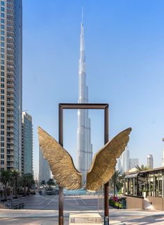 an angel statue in the middle of a city square with skyscrapers in the background