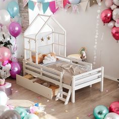 a doll house bed with balloons and confetti all around it in a bedroom