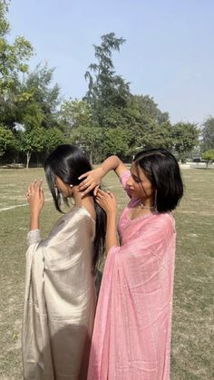 two women standing next to each other in a field