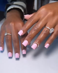 a woman's hands with pink and white manicures on their nails, holding onto her engagement ring