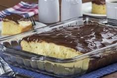 a cake in a pan with chocolate frosting on top and two plates next to it